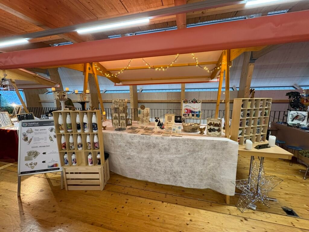 Indoor market stall with wooden beams, string lights, and handmade crafts on display in a well-lit hall.
