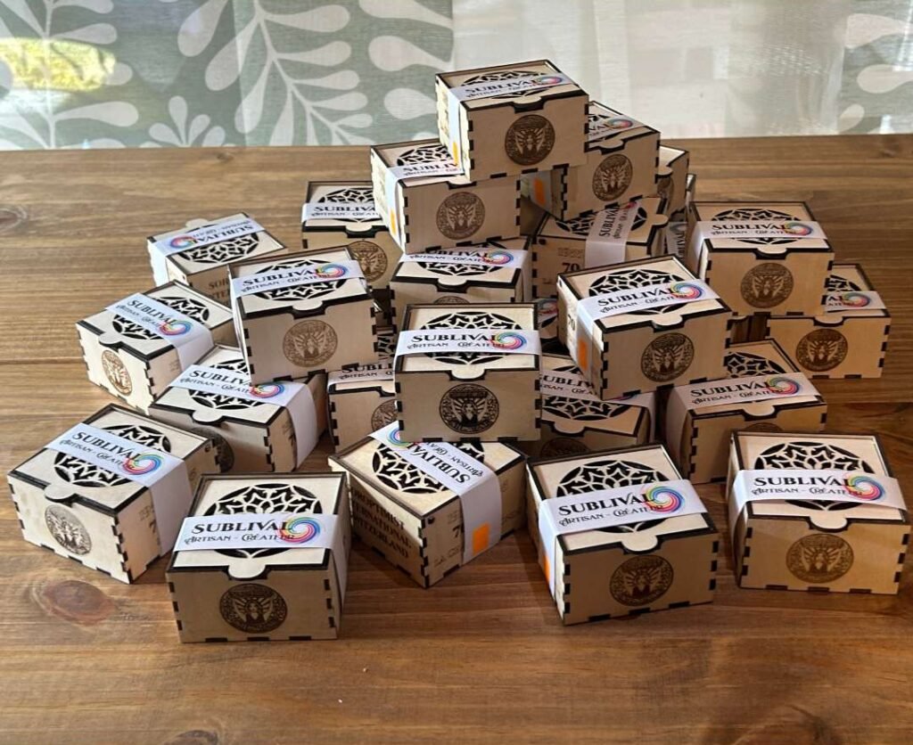 Pyramid of small brown cardboard boxes with black decorative panels and SUBLIV A label on a wooden table.